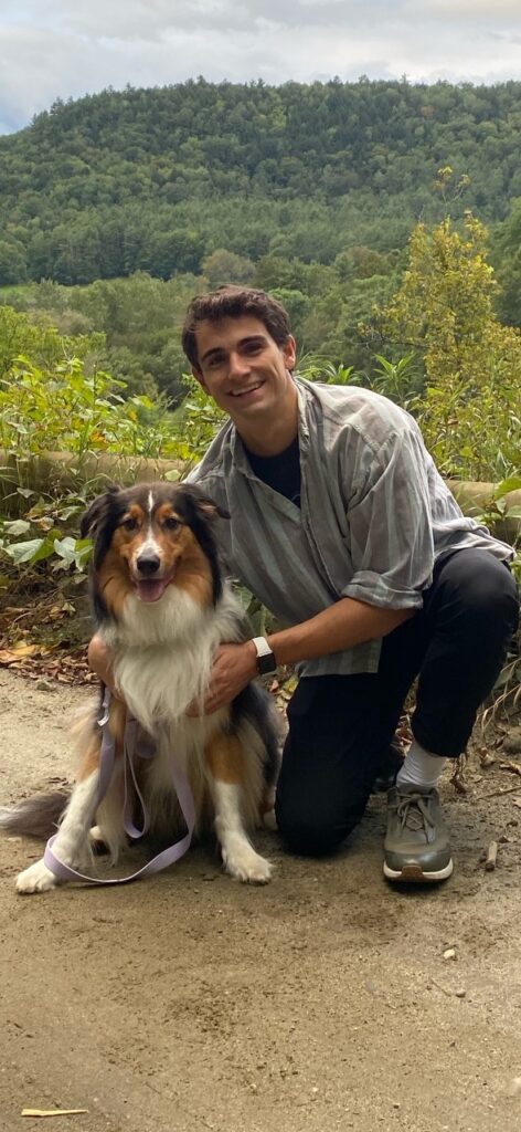 Dawson next to his dog while hiking with a mountain in the background