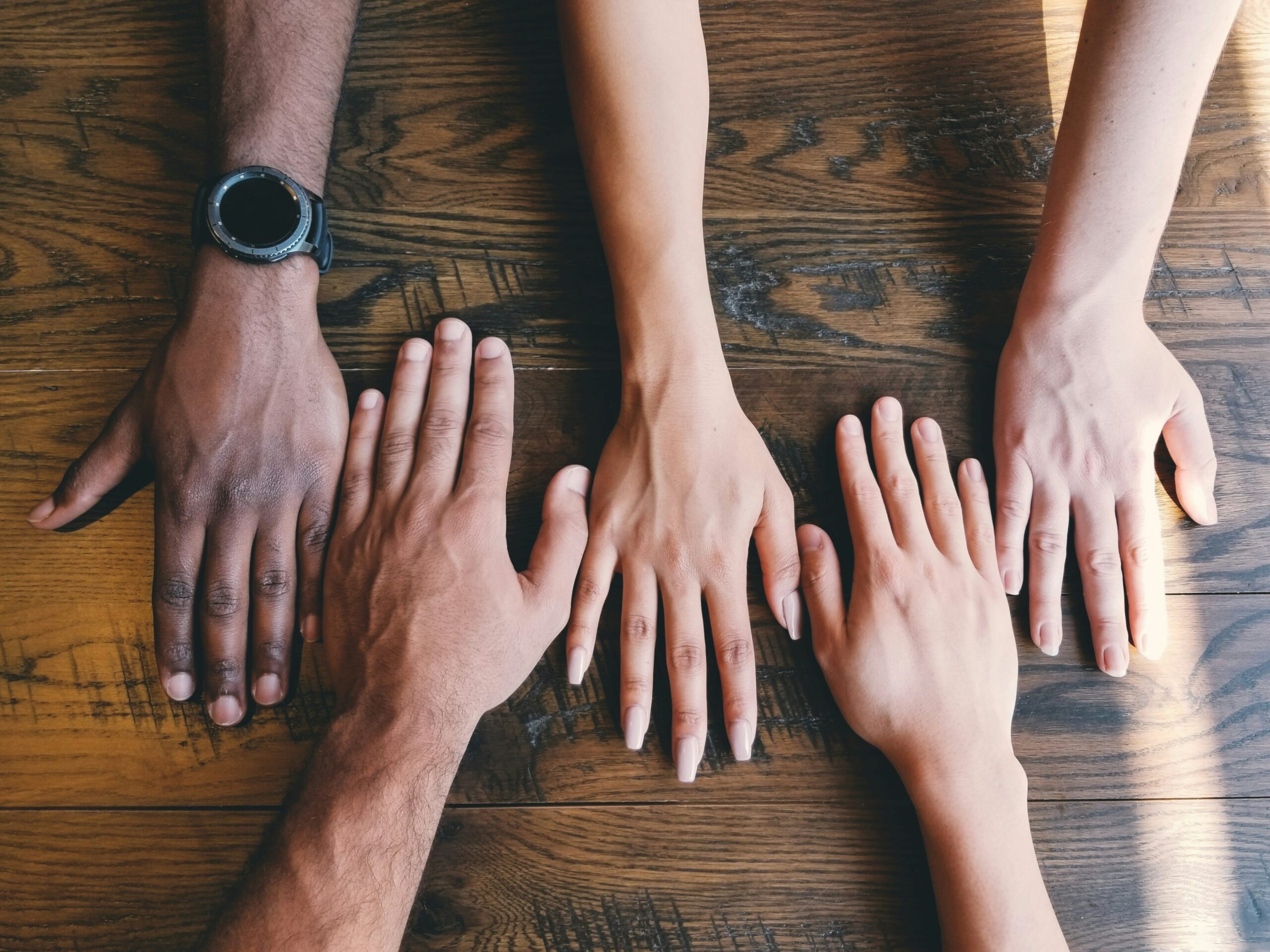 Five hands on a table representing diversity